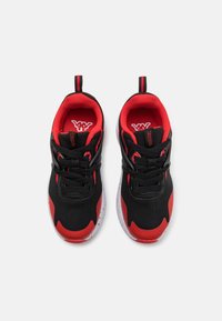 Černé a červené sportovní boty s vrchní částí z prodyšné síťoviny, polstrovaným límcem a černými tkaničkami. Mají rozprášenou bílou podrážku a logo na jazyku.