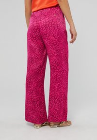 Roze wijde broek met een gedurfde luipaardprint. Gemaakt van lichtgewicht stof met een soepele textuur en een gouden accent op de achterzak.