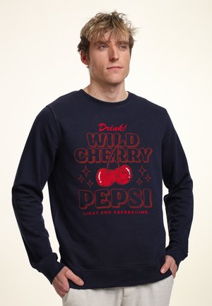 Felpa di colore blu navy con una stampa rossa di ciliegie e il testo "Wild Cherry Pepsi". Design semplice con polsini a coste e scollatura a girocollo.
