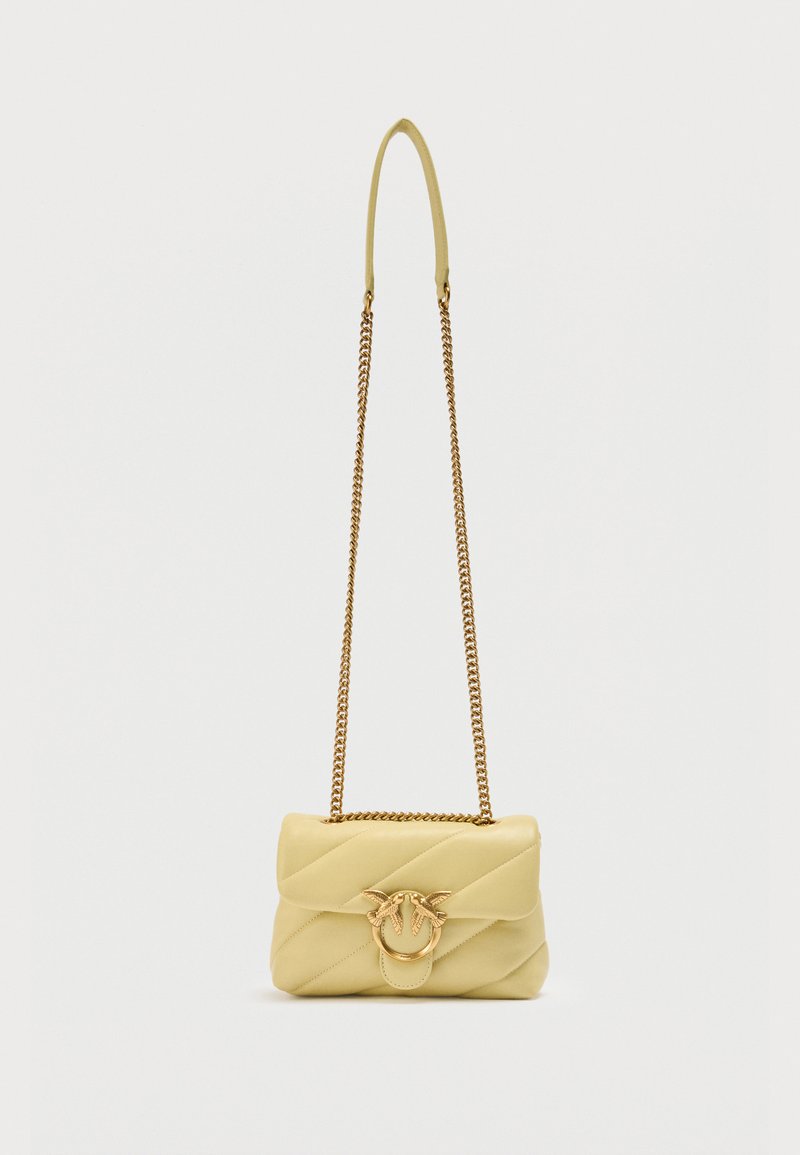 Μικρό καπιτονέ ανοιχτόκίτρινο δερμάτινο τσαντάκι ώμου με χρυσή αλυσίδα λουρί και διακοσμητικό κούμπωμα σε σχήμα χρυσού πουλιού.