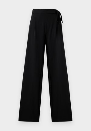Pantalons larges noirs en tissu lisse avec une taille haute et un détail noué. Ils ont une silhouette fluide et décontractée.