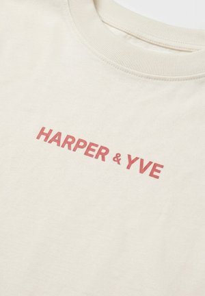 T-shirt couleur crème à col rond avec texte rouge "HARPER & YVE" imprimé sur la poitrine.