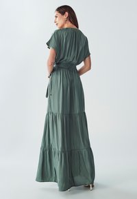 Dlouhá zelená maxi šaty s krátkými rukávy, v třívrstvém designu, z měkké látky a s páskem v pase, s volnou sukní a jemným drapováním.
