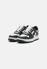 Sneakers in pelle bianca e nera con punta arrotondata, spesse stringhe bianche, linguetta imbottita e suola in gomma testurizzata. Abbelliti con dettagli del logo.