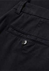 Černé látkové kalhoty s zadní kapsou na knoflíkovou uzávěr a jemnou ribbovou texturou, s pečlivě prošitými detaily podél okrajů.