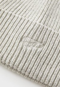 Gray knitted beanie with ribbed texture and subtle logo embroidery. Soft wool material, featuring vertical lines and a fold-over cuff.