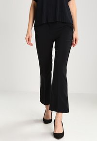 Svarta utsvängda byxor i ett mjukt, elastiskt material. Designade med hög midja och skräddarsydd passform, kompletterade med en subtil lyster.