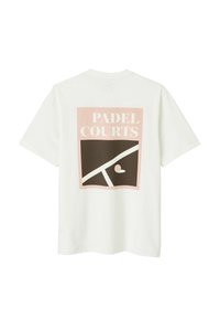 T-shirt en coton blanc avec un grand graphisme au dos comportant le texte "PADEL COURTS" en rose et marron, accompagné d'éléments abstraits de terrain.