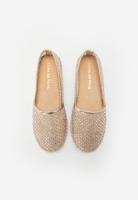 Beige vevde espadriller med et teksturert mønster, metallisk kant rundt åpningen, og en glatt innvendig foring. Flatt såledesign.