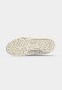 Σόλα ελαφρώς μπεζ παπουτσιού Reebok με διαμάντι ανάγλυφο και κυκλικό σχέδιο λαβής σε λευκό φόντο.