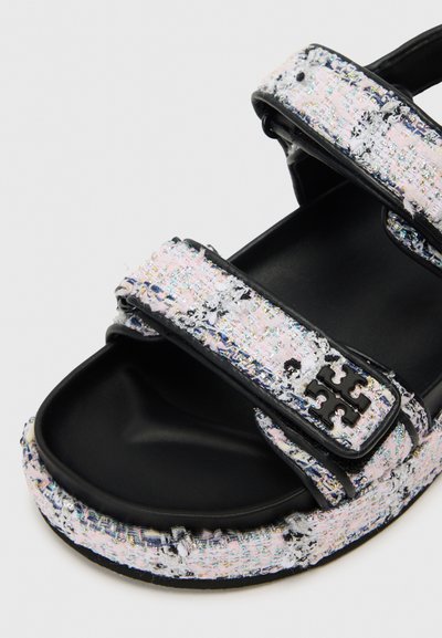 Fekete szandál, textúrált rózsaszín és fehér szőtt pántokkal, állítható tépőzáras záródással és fényes fekete akcentussal az oldalon.