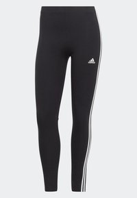 Svarta leggings i stretchigt material, med vita sidosträngar och en Adidas-logotyp på nedre vänstra benet.