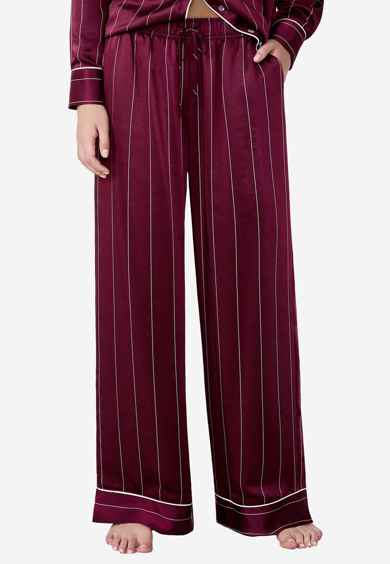 Burgundy silk pyjamasbyxor med vita vertikala ränder. Har en dragsko i midjan och en vid skärning, som framhävs av kontrasterande fålldetaljer.