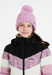 Rožinė megzta kepurė su pom-pomu, derinama su juoda ir rožine raštuota slidinėjimo striuke, turinčia spalvų blokavimą ir užtrauktuką.