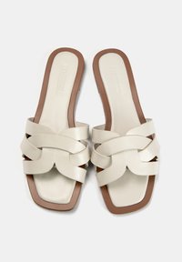 Sandales à glisser en cuir blanc avec un design de sangle tissée, bout carré et semelle marron. Texture lisse avec des accents matériels minimaux.