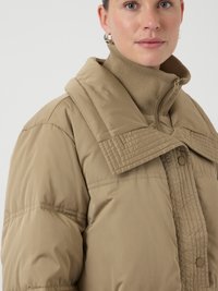 Giacca puffer beige con colletto alto, texture a righe verticali e chiusura a bottoni a pressione. Tessuto liscio e leggero con vestibilità comoda.