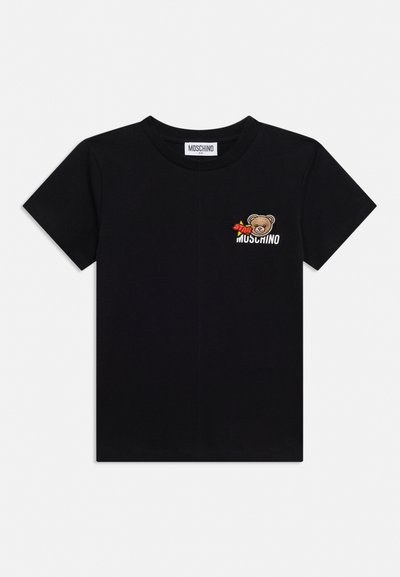 Tricou negru cu mâneci scurte, cu fața unui urs brodat mic, o stea roșie și text alb "MOSCHINO" pe partea stângă sus a pieptului.