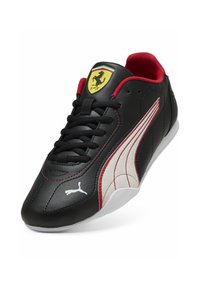 Musta nahkainen lenkkarit, joissa on punaisia yksityiskohtia, valkoinen Puman raita, Ferrarin logo kielen päällä, mustat nauhat ja sileä pinta. Matala profiili.