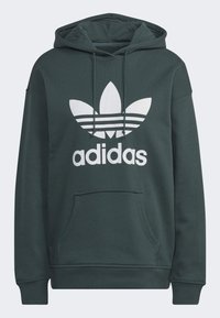 Mörkgrön hoodie i bomull med en stor vit Adidas-logotyp och tre ränder samt en framficka i kängurustil.