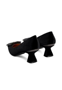 Zapatos de ante negros de tacón bajo con tacones en bloque geométricos y adornos decorativos de joyas en la parte frontal.