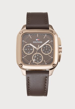 Montre-bracelet carrée en finition dorée avec un bracelet en cuir marron, un cadran brun, trois sous-cadrans et des aiguilles des heures et des minutes avec extrémités blanches.