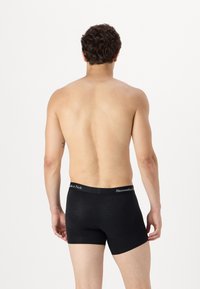 Sorte bomulds boxershorts med elastik i taljen, der har "Abercrombie & Fitch" logo. Modellen ses fra ryggen.