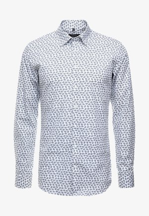 Chemise blanche à manches longues avec boutons, ornée d'un petit motif floral bleu et d'un col large.