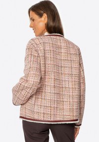 Teksturowana różowa kurtka z tweedu o wzorze w kratę, kontrastującymi bordowymi wykończeniami oraz luźnym krojem. Miękka tkanina o przytulnym odczuciu.