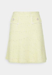 Keltainen tweed-minihame, jossa on istuva vyötärö, kaksi etutaskua ja koristeelliset helmipainikkeet. Hameessa on repaleinen helma ja hillitty metallilanka.