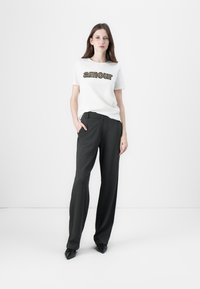 White t-shirt with "amour" printed in a patterned font, paired with charcoal gray wide-leg trousers and black pointed shoes.