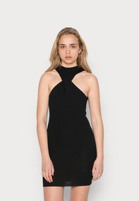 Sundress preto de malha canelada com um colo alto, apresentando um design de recorte assimétrico nos ombros e uma silhueta ajustada.