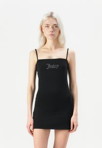 Robe mini noire à fines bretelles, avec un logo métallique "Juicy" sur la poitrine. Tissu extensible et design ajusté.
