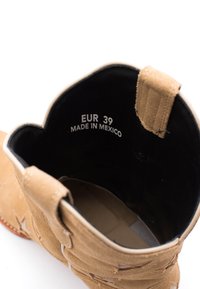Stivale alla caviglia in suede tan con parte superiore scallop, interno nero e taglia stampata "EUR 39" e "MADE IN MEXICO" all'interno.