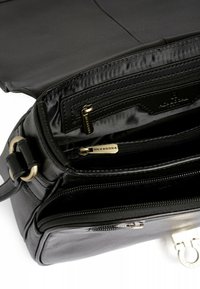 Borsa a tracolla in pelle nera con scomparti zip multipli, texture liscia e un accentuazione in metallo dorato. L'interno presenta una fodera in tessuto.