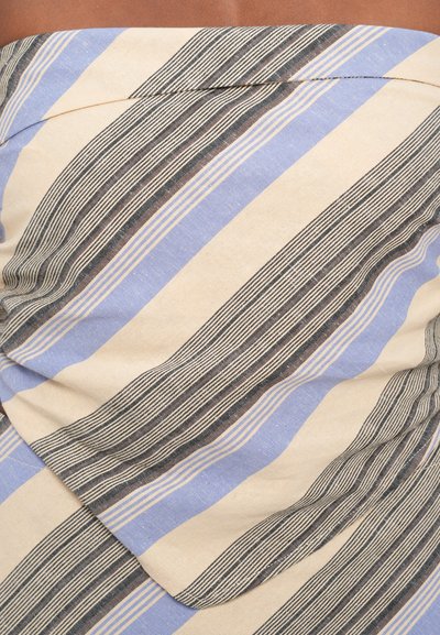 Beige tyg med diagonala ränder i blått, svart och kräm. Mjuk textur med en något skrynklig yta som visar ett lagerdesign.