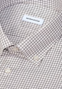 Chemise blanche à motif quadrillé noir fin, col boutonné et une étiquette blanche portant l’inscription "seidensticker" à l’intérieur du col.