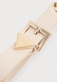 Beige faux leather belt featuring a gold metal buckle and triangular logo plate engraved with "GUESS U.S.A."