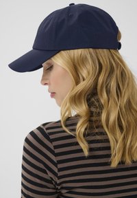 Navy baseball cap with a curved brim, made of lightweight fabric. Features stitching details and an adjustable strap at the back.