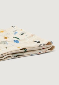 Pătură din muselină de bumbac, crem cu modele colorate de animale și natură, textură moale, pliată într-un unghi care scoate în evidență marginea și detaliile imprimeului.