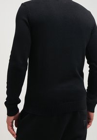 Schwarzer Strickpullover mit langen Ärmeln, gerippten Bündchen und Saum, glatter Textur, taillierter Passform sowie ohne sichtbare Muster oder Metalldetails.