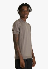 Maglione marrone a maniche corte con scollo rotondo e polsini a costine, caratterizzato da una texture liscia e un taglio aderente.