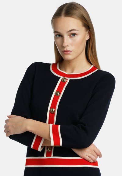 Navy long-sleeve sweater with a red and white striped trim and gold buttons down the front. Soft texture and fitted design.