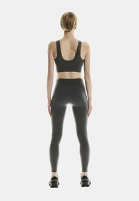 Tumehall sportbra sükærliku seljaga, mille juurde kuuluvad sobivad kõrge talje jalgpüksid. Omab mugavat istuvust ja sujuvat tekstuuri. Mustad spordijalatsid.