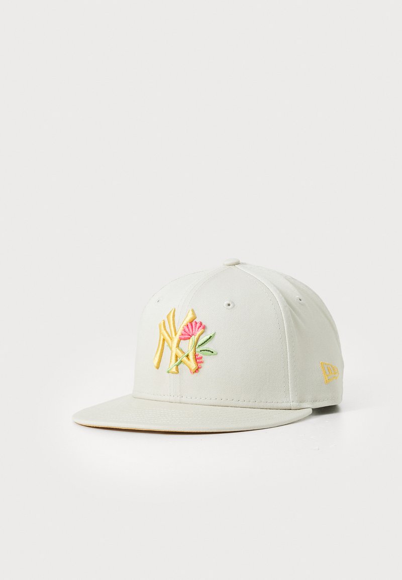 Lys grå caps laget av stoff med en buet skjerm. Har brodert logo i gult og rosa med blomsterdetaljer. Klassisk design.