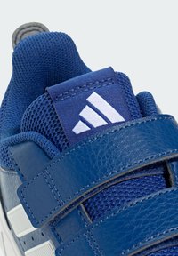 Niebieski but sportowy z cholewką wykonaną z teksturowanej skóry i siateczki, zapinany na rzepy, z białym logo w postaci trzech pasków.