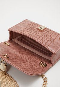 Růžová crossbody kabelka z imitace kůže s texturovaným hadím vzorem, zlatými kovovými prvky, řetízkem a vnitřní kapsou na karty. Magnetické uzavírání.