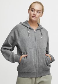 Gray zip-up hoodie with adjustable drawstrings, large front pockets, and ribbed cuffs. Soft fabric with a smooth texture.
