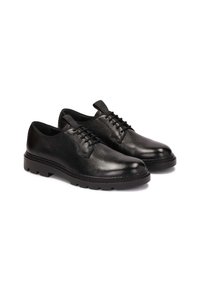 Zapatos de cuero negro con cordones, acabado texturizado, puntera redondeada y suela de goma gruesa con profundos surcos para un mejor agarre.