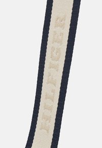 Cintura intrecciata blu navy con superficie texturizzata, caratterizzata da una striscia avorio impressa con la parola "HILFIGER."
