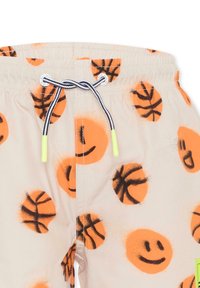 Costumi da bagno beige con motivo di palloni da basket arancioni e faccine sorridenti, vita elastica con cordoncino nero e bianco, e etichetta verde.